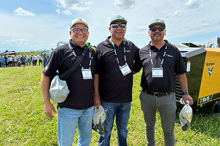 Raymundo Badillo stands in a field with two of his colleagues in front of a Vermeer directional drill
