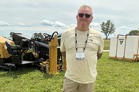 Andrew Hughes posing a field in front of a Vermeer directional drill and mix system