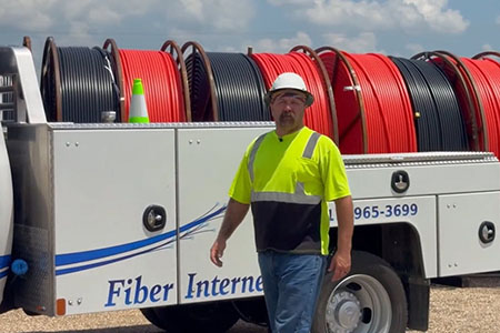 Joe Royer walks in front of his work truck wearing PPE