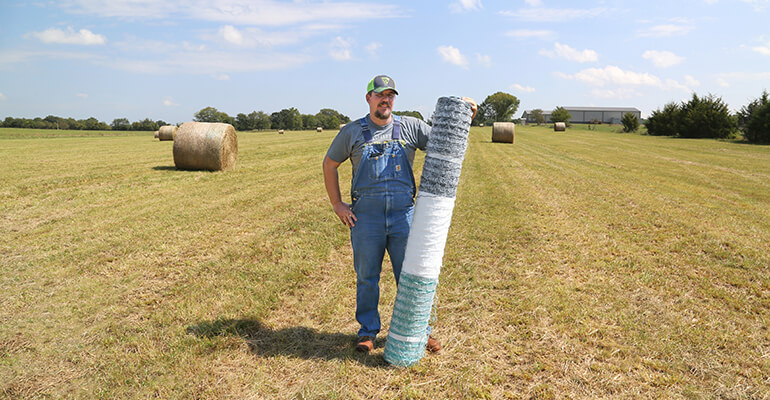 Farmer Tyler Knight posting with a roll of Vermeer netwrap