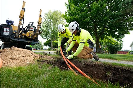 Two HDD crew members working on a bore with a Vermeer horizontal directional drill